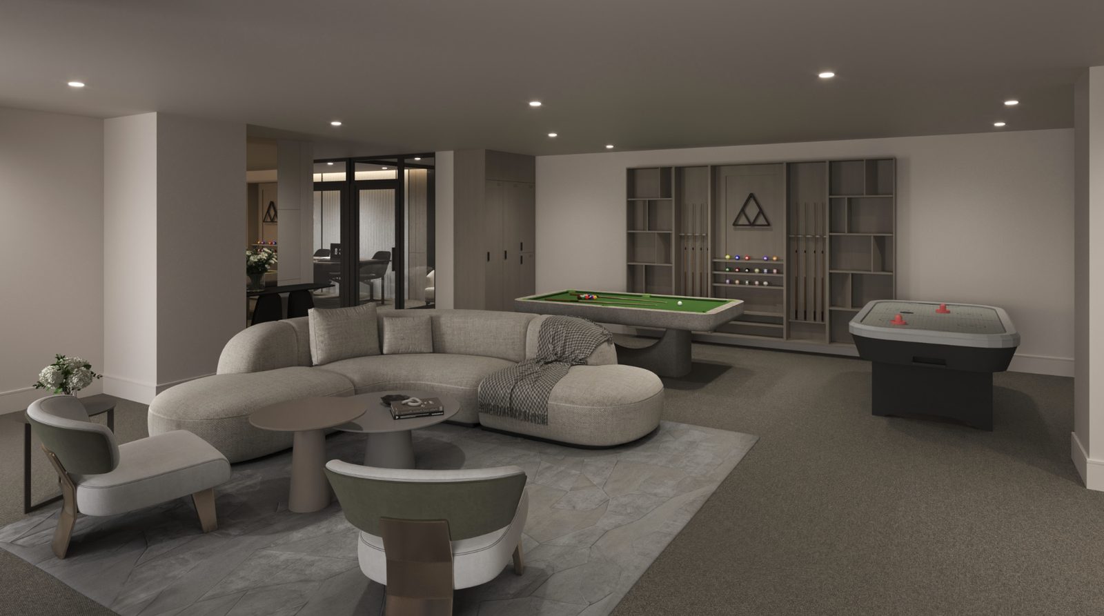 A shared lounge with a curved sofa and armchairs, and a pool table and air hockey table behind.